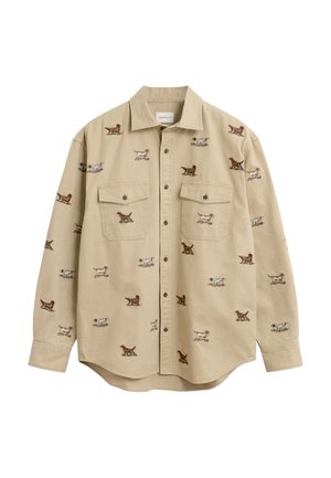 Chemise beige à boutons avec col et poches poitrine, ornée d'un motif de petits chiens marron et blancs dans différentes poses.