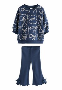 Marinblå sweatshirt med vita rosett-mönster och ribbade manschetter, tillsammans med matchande utsvängda byxor med volangkant och rosetter på sidorna.