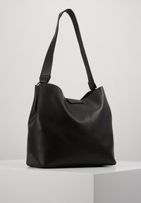 Czarna skórzana torba hobo o fakturowanej powierzchni, zaokrąglonym wierzchu, pojedynczym regulowanym pasku oraz subtelnym magnesowym zapięciu.
