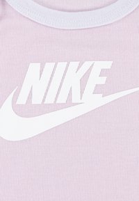 Nike bez rukava u svijetloplavom rebrastom materijalu. Ima istaknuti bijeli logo s zakrivljenim naglaskom i kontrastnim okruglim izrezom.