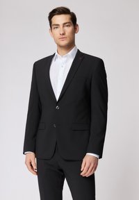 Il blazer nero presenta una vestibilità su misura, un design a un petto, rever a scollatura, due tasche frontali e un tenue accento rosso sul colletto.