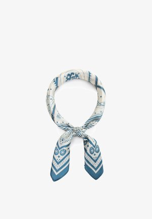 Foulard quadrato di seta con motivi paisley e geometrici blu e bianchi, annodato con un nodo sciolto.