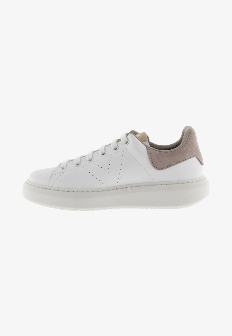Sneaker in pelle bianca con fascetta sul tallone in suede beige, punta rotonda e perforazioni sulla punta. La suola piatta in gomma e i lacci bianchi completano il design.