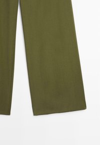 Pantalons larges vert olive en tissu lisse. Dotés d'une finition soignée sans matériel ou motifs visibles.