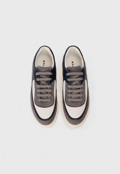 Adidași cu șireturi, cu o talpă plată. Partea superioară este realizată din piele și suede gri, bleumarin și crem, având un design modern. Talpă de un bej deschis.