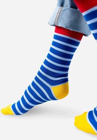 Skarpetki w różnych kolorach z niebieskimi i jasnoniebieskimi poziomymi paskami, z żółtymi akcentami na palcach i piętach oraz czerwoną mankietą.