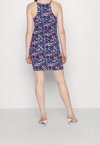 Abito con motivo floreale caratterizzato da uno sfondo navy con fiori rosa, bianchi e blu. Design senza maniche con una silhouette aderente, lunghezza sopra il ginocchio.