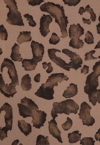 Tissu imprimé léopard avec de grandes taches brun foncé sur un fond beige clair, offrant une finition douce et texturée.