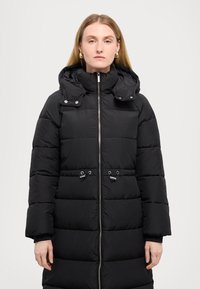 Cappotto imbottito nero con chiusura zip frontale, cappuccio rimovibile e coulisse elastica in vita. Presenta un design trapuntato e chiusure a scatto.