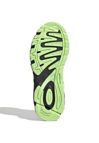 Svart och neongrön sportskosula med ett texturerat mönster, som har spår och cirkulära mönster för trygghet och stabilitet.