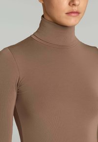 Maglione a collo alto marrone con vestibilità slim. Realizzato in un tessuto morbido e liscio con una texture a coste. Collo alto e maniche lunghe.