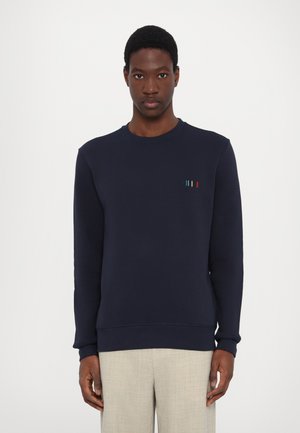 Sweatshirt bleu marine en mélange de coton avec un col rond. Présente des rayures verticales multicolores subtiles sur la poitrine gauche. Poignets et ourlet côtelés.