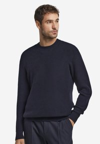 Marinblå stickad tröja med en texturerad ribbad design, rund halsringning och långa ärmar. Har en avslappnad passform vid fållen och ärmsluten.