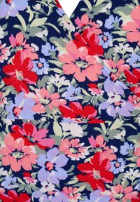 Květinová tkanina má tmavě námořnické pozadí s velkými červenými, růžovými a levandulovými květinami, doplněnými zeleným listím. Měkký, texturovaný materiál.