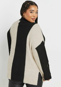 Sweter kardigan z czarno-kremowymi paskami, golfem, rozcięciami po bokach i detalami z guzikami na rękawach. Miękka tekstura i luźny krój.