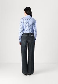 Blue striped button-up shirt with small black patterns, paired with high-waisted, wide-leg dark denim jeans.
