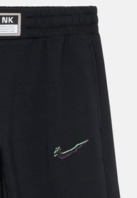 Svarta mjukisbyxor med elastisk midja, med en flerfärgad Nike-logga broderad på vänster lår. Mjuk tygkänsla.