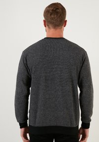 Hall ristiga hall kangas sweatshirt, millel on ümmargune kaelus, mustad soonikuvarrukad ja äär, ning millel on kangal peen mustri. Tagakülje vaade.