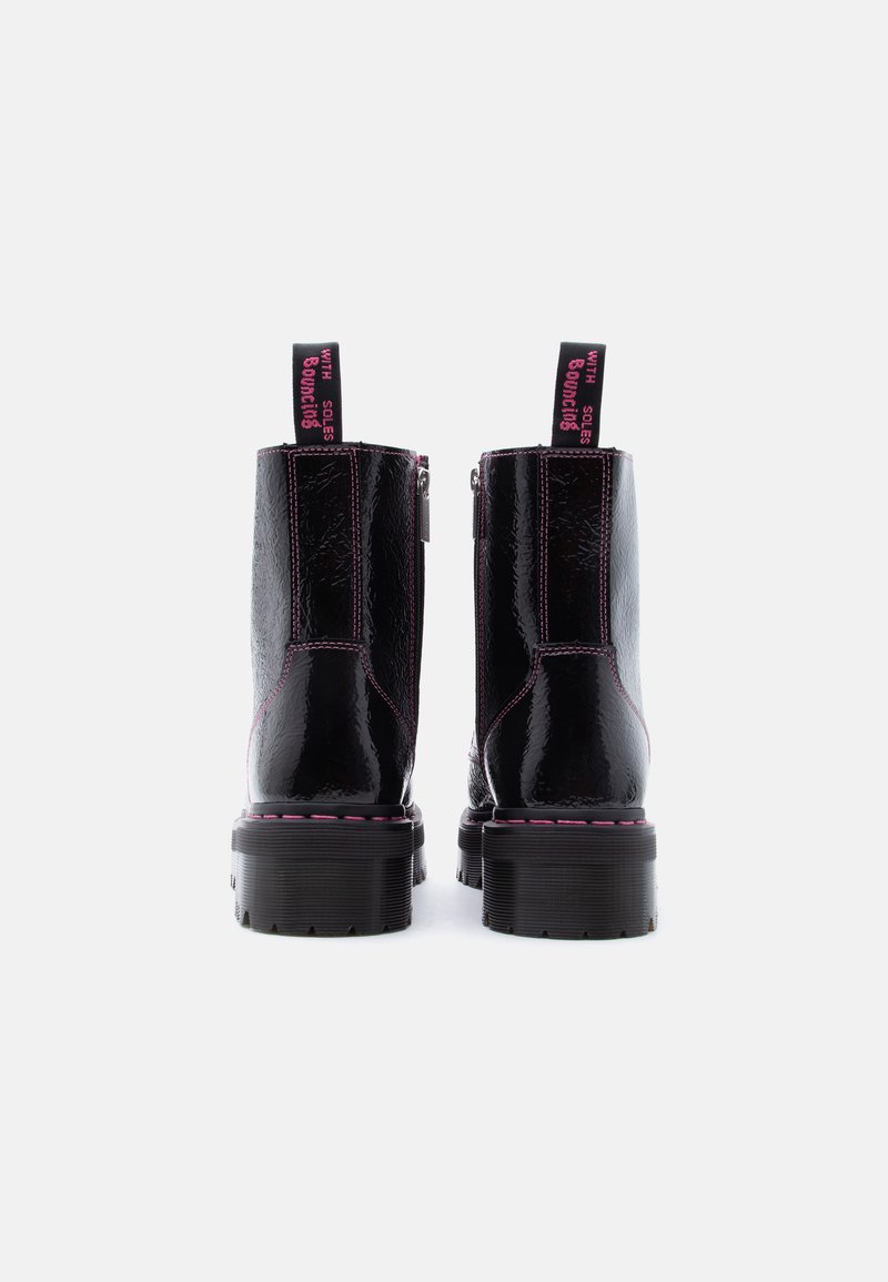 Zwarte glanzende plateau laarzen met roze stiksels en trekriempjes met de tekst "WITH SOLES BOUNCING," gezien van achteren tegen een witte achtergrond.