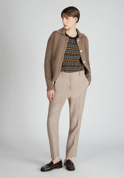 Brązowa kurtka o teksturze z dużymi guzikami, wzorzysty ciemny sweter, jasnobeżowe dopasowane spodnie i ciemne loafersy. Prosty i elegancki design.