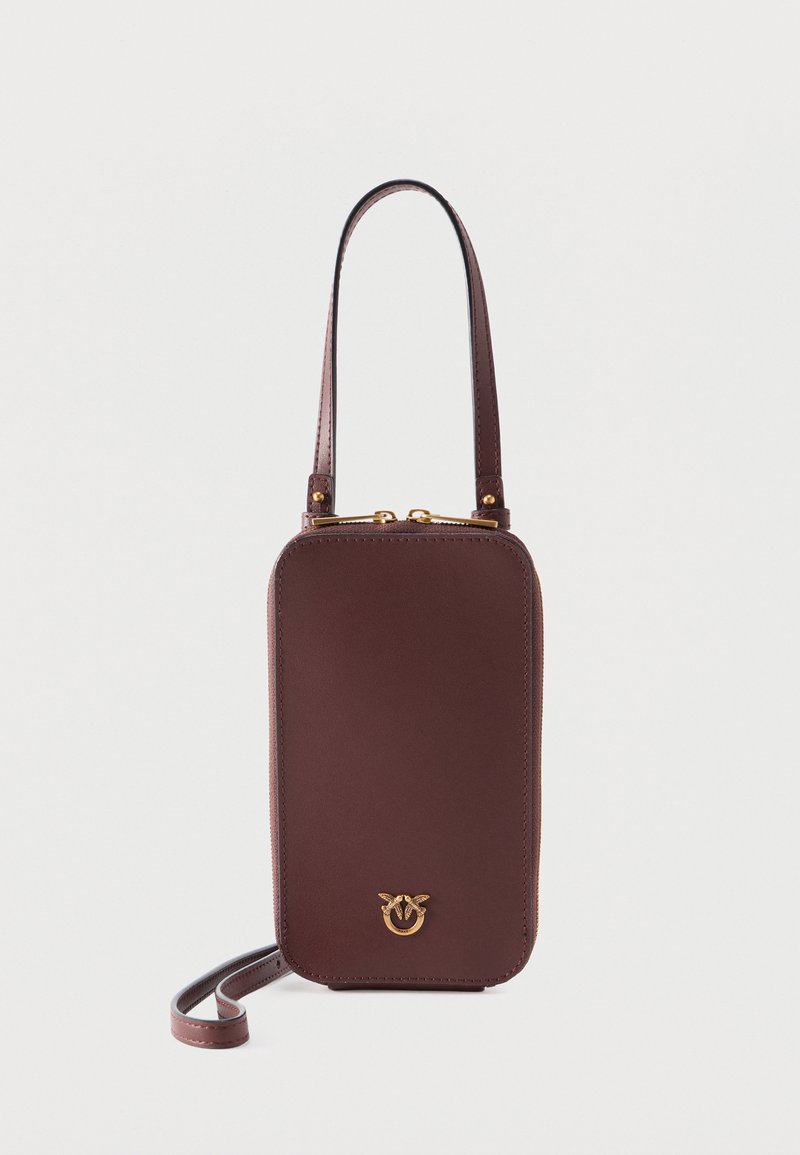 Μικρή κάθετη καφέ δερμάτινη τσάντα με χρυστό φερμουάρ και λογότυπο, με κοντή λαβή και μακρύ αποσπώμενο ιμάντα.