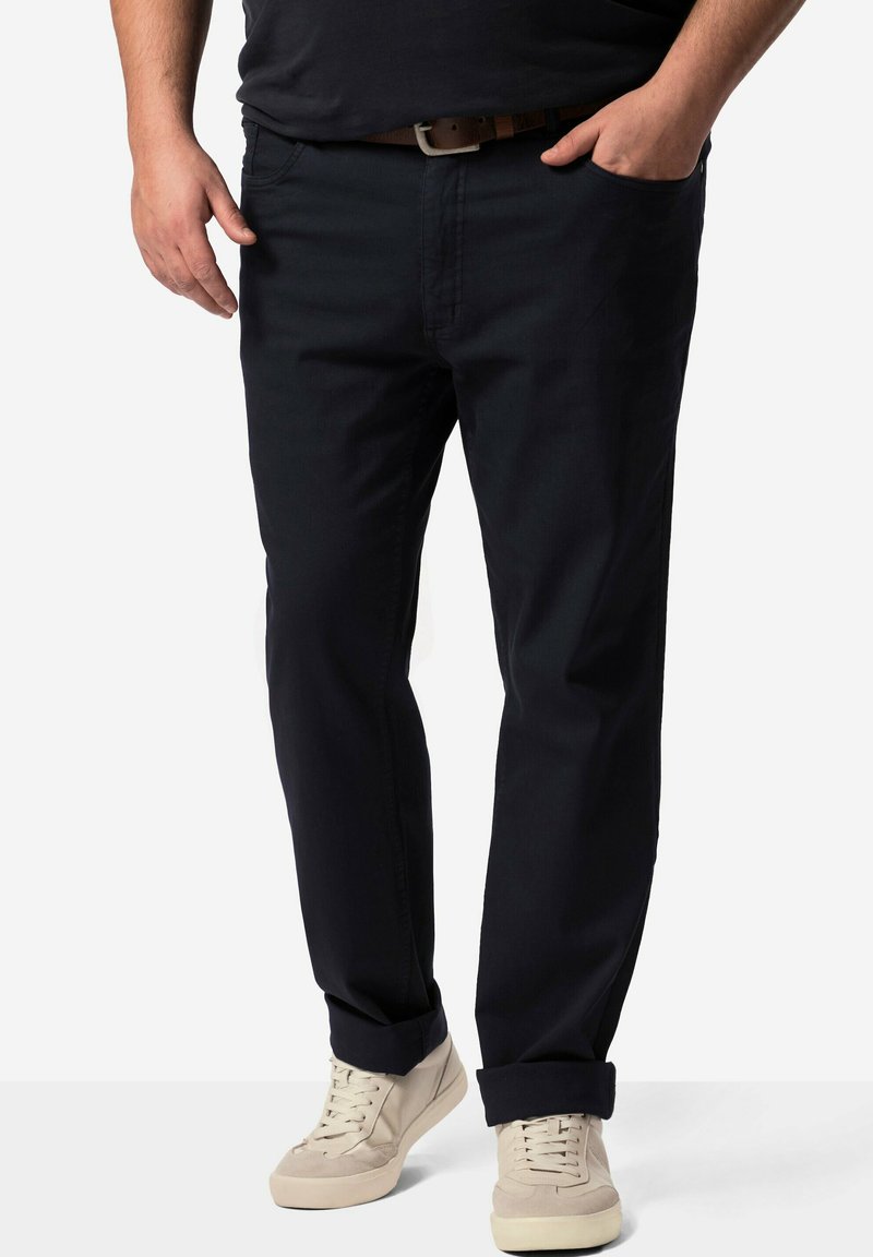 Chinos azul oscuro fabricados en una mezcla de algodón, con diseño de pierna recta, bolsillos frontales y puños doblados, combinados con zapatillas ligeras.