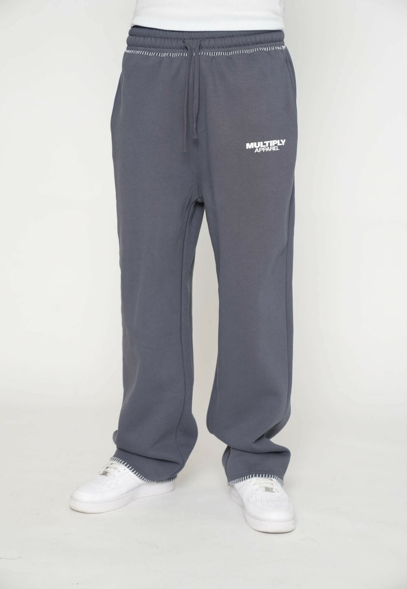Sivé teplákové nohavice s uvoľneným strihom, elastickým pásom a šnúrkou. Na prednej strane sa nachádza biele logo "MULTIPLY APPAREL" a rebrované manžety.