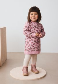 Robe en tricot rose avec imprimé léopard, poignets et ourlet côtelés. Collants en tricot crème et bottes roses avec bordure en fausse fourrure et pompons.