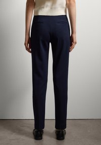 Pantaloni navy realizzati in tessuto liscio, progettati con una vestibilità su misura, tasche posteriori piatte e un taglio dritto.