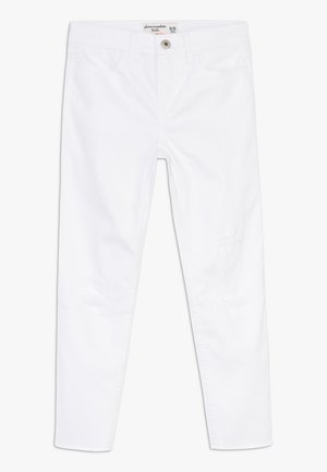 Vaqueros de mezclilla blancos con un ajuste slim, que cuentan con cierre de botones, bolsillos delanteros y sutiles detalles desgastados cerca de las rodillas.