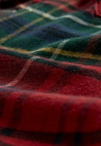 Tela de franela de tartán en rojo, verde y azul con un patrón de cuadros audaz; textura suave, fibras visibles y líneas de cuadros contrastantes.