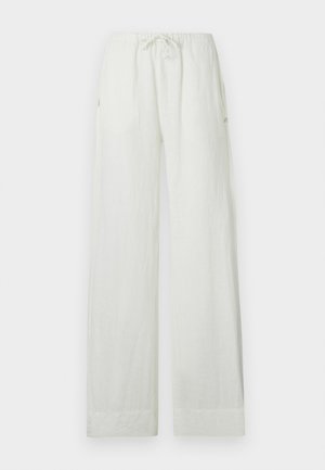 White loose linen pants with elastic waistband and drawstring, featuring straight wide legs and side pockets.