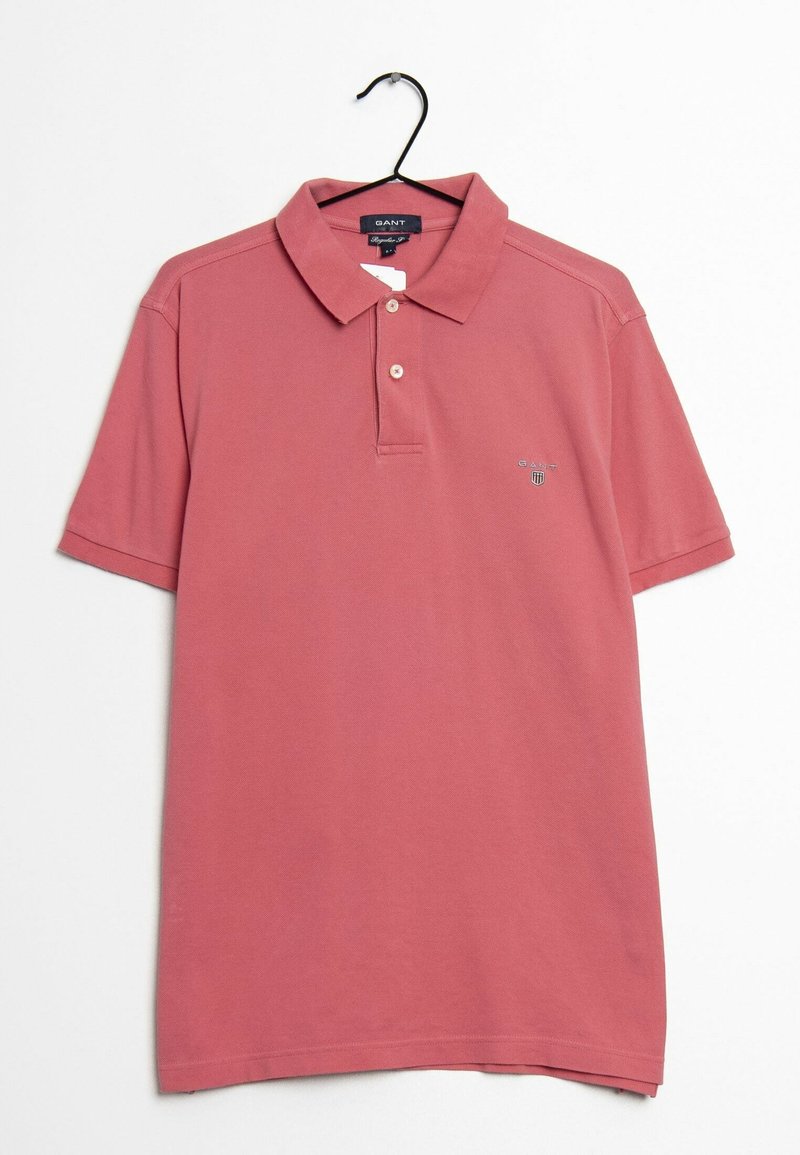 Koszulka polo z krótkim rękawem w stonowanym odcieniu różu, wykonana z bawełny. Posiada kołnierzyk, trzy guziki oraz małe logo na piersi. Wisi na wieszaku.