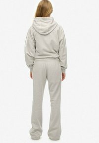 Light gray hooded sweatshirt with a relaxed fit, paired with matching gray sweatpants. Material appears soft and textured, with elastic waistband.