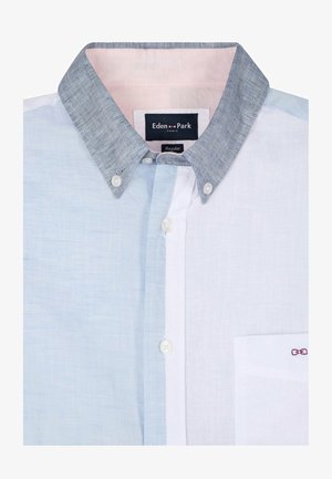 Chemise boutonnée avec panneaux bleu clair et blanc, col boutonné gris, boutons blancs et petit logo nœud rose sur la poche poitrine.