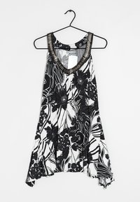 Débardeur floral noir et blanc avec une coupe ample, un décolleté en V profond et un col texturé rehaussé de métal. Tissu léger avec des motifs floraux.