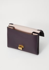 Leather handbag with a dark purple exterior, smooth texture, light pink top flap, and gold hardware clasp at the front.