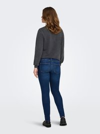 Grijze sweatshirt met een ronde hals en lange mouwen, gecombineerd met donkerblauwe skinny jeans met achterzakken en een gladde textuur.