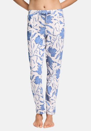 Witte broek met blauw bloemenpatroon en een trekkoord in de taille, gedragen door een blotevoeten persoon die met de handen achter de rug staat.