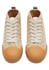 Bežové vysoké tenisky s texturovaným chlupatým svrškem, krémovými tkaničkami a gumovým světlým špičkou. Obsahují akcentační smyčku na zadní straně pro snadné obouvání.