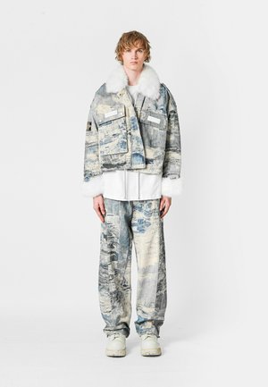 Conjunto de chaqueta y pantalones de mezclilla en tonos de azul y gris con un suave cuello y puños de piel sintética blanca; múltiples bolsillos, ajuste holgado.