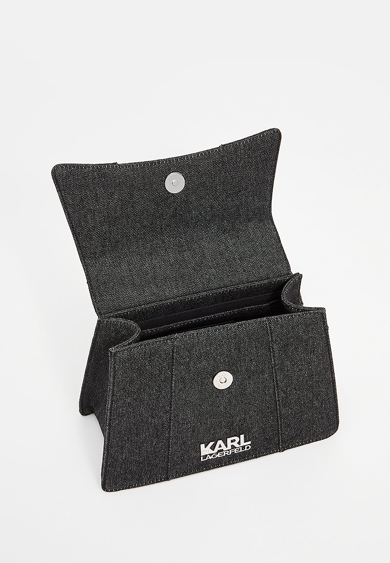 Portefeuille en denim noir avec fermeture à rabat, bouton-pression argenté, deux compartiments et accents cousus. Présente le logo sur le devant.