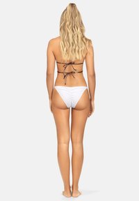 Biały bikini o strukturalnym wykończeniu, minimalnym kryciu i regulowanych czarnych sznurkach z tyłu. Gładki materiał i wysoki krój nogawki.