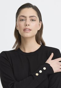 Czarny dzianinowy sweter z okrągłym dekoltem i trzema dekoracyjnymi złotymi guzikami na mankiecie. Gładka tekstura i dopasowany krój.