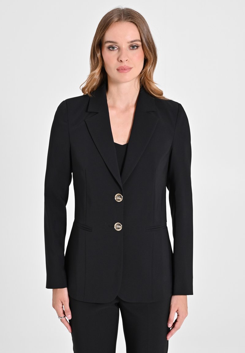 Blazer nero su misura realizzato in tessuto liscio con un design strutturato, revers a scudetto, due bottoni dorati e tasche laterali.