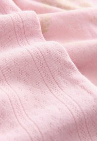 Tissu tricoté rose doux avec des rayures surélevées délicates et des motifs floraux, montrant une texture détaillée et des plis doux.
