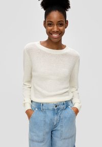 Helle, gestrickte Cremefarbenen Pullover mit weitem Ausschnitt und gerippten Bündchen, kombiniert mit hellblauen Denim-Shorts mit Fronttaschen.