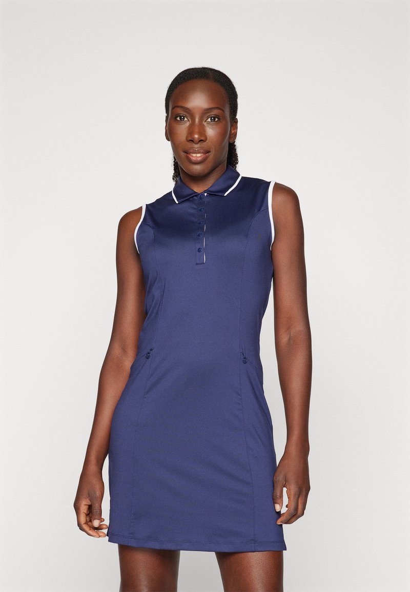 Vestido polo sem mangas azul-marinho com gola, abertura de cinco botões e detalhes brancos contrastantes nos ombros e na barra.