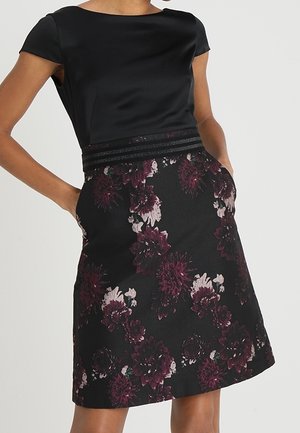 Czarna sukienka z dopasowanym satynowym gorsetem i plisowaną spódnicą w kwiatowy wzór z bordowymi i białymi kwiatami. Zawiera dyskretne boczne kieszenie.