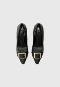 Pantofi cu toc înalt din piele neagră, cu un design cu vârf ascuțit, având o curea lată neagră decorată cu un detaliu de cataramă aurie.